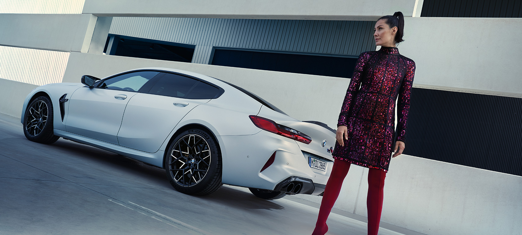 BMW M8 Competition Gran Coupé F93 LCI modernizacja 2022 mroźna brylantowa biel BMW Individual metalizowany tylny półprofil z modelką obok pojazdu