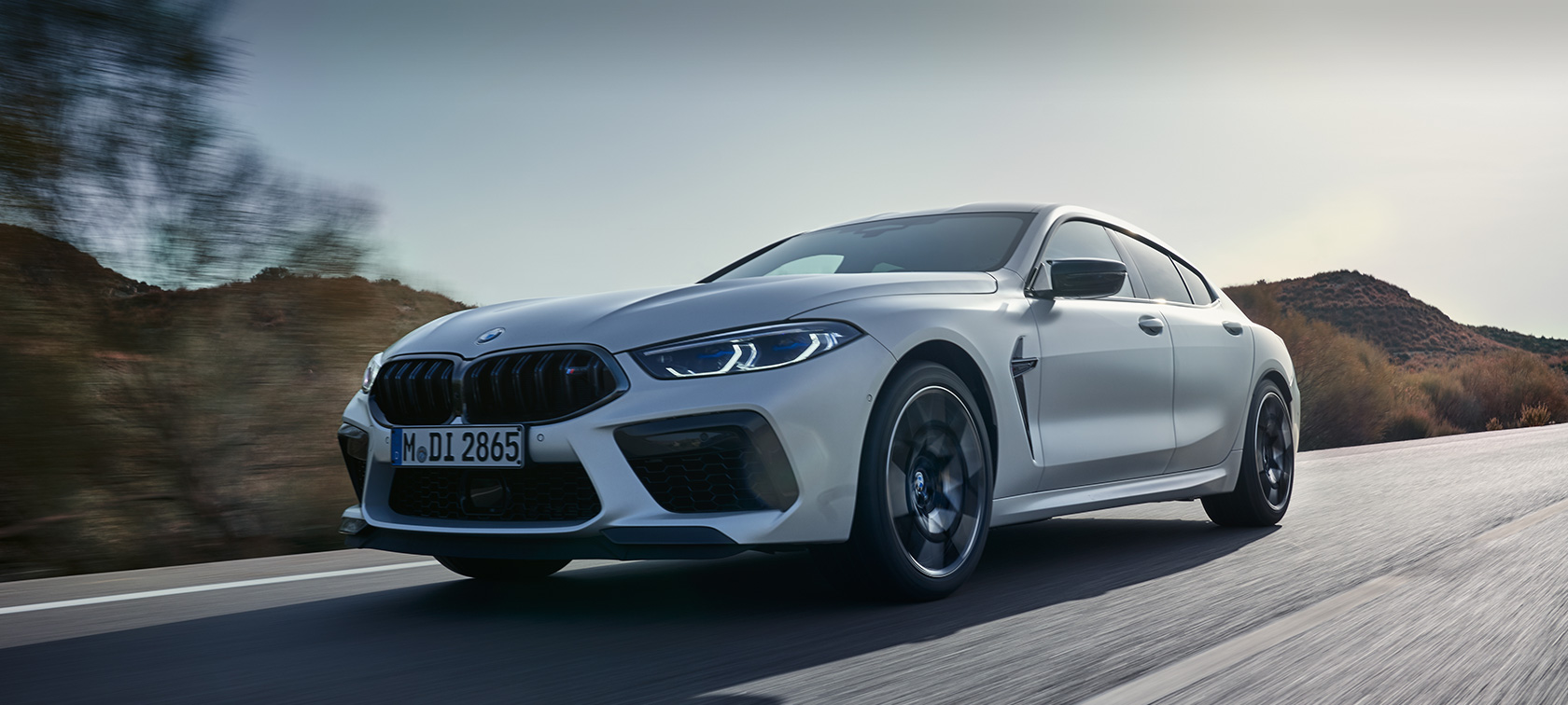 BMW M8 Competition Gran Coupé F93 LCI modernizacja 2022 mroźna brylantowa biel BMW Individual metalizowany przedni półprofil podczas jazdy