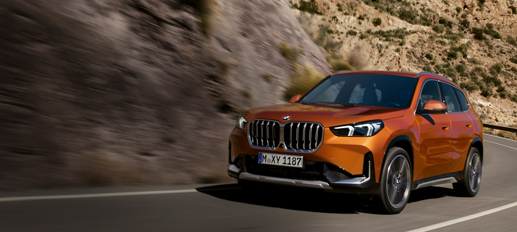 BMW X1 U11 xLine pomarańczowy Utah metalizowany przedni półprofil podczas jazdy za miastem